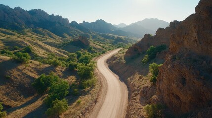 Scenic dirt road winding through rugged mountain landscape aerial view