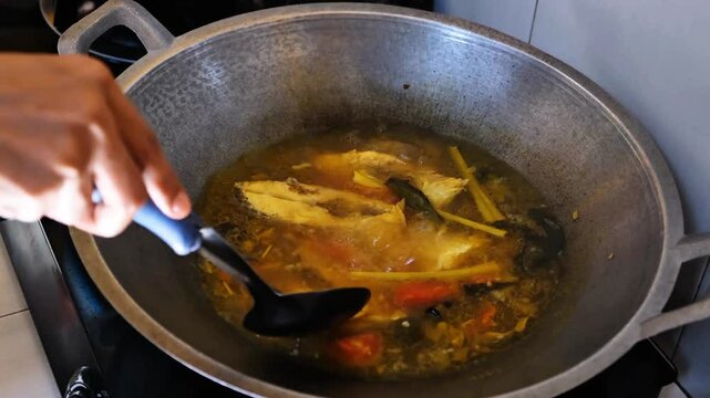 cooking aromatic yellow soup of red snapper fish with chili