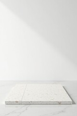 Elegant off-white terrazzo platform on a marble surface against a minimalist white wall, ideal for product display or showcasing design