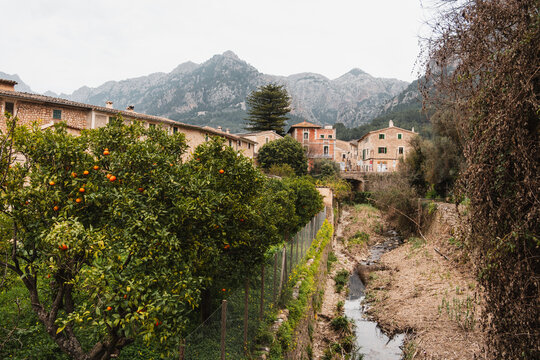 S&oacute;ller, Mallorca, Spain - Orange Trees, a creek and Stone Houses in S&oacute;ller, Mallorca. Serene Winter without snow. Landscape with Mountain Backdrop