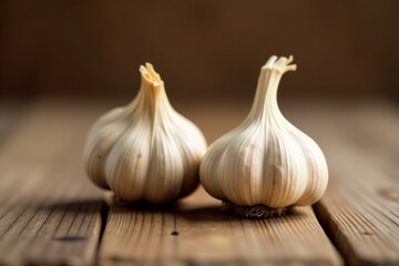 Obraz premium Two whole heads of garlic bulbs rest on rustic wooden planks, illuminated by soft natural light.
