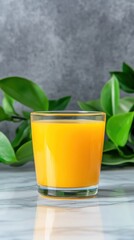 Fototapeta premium Fresh pressed orange juice in glass still life with greenery backdrop