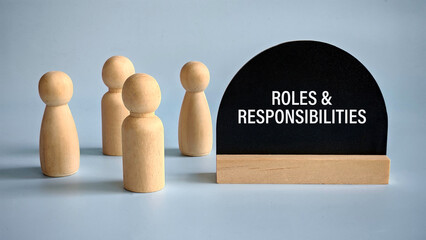 A group of wooden people stand beside sign of Roles and Responsibilities.