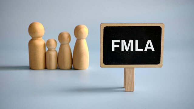 A sign written FMLA Family and Medical Leave Act with a wooden family behind over blue background.