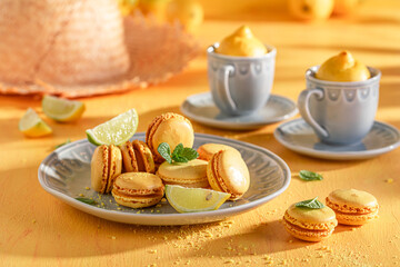 Tasty and homemade lemon macarons on blue plate with mint.