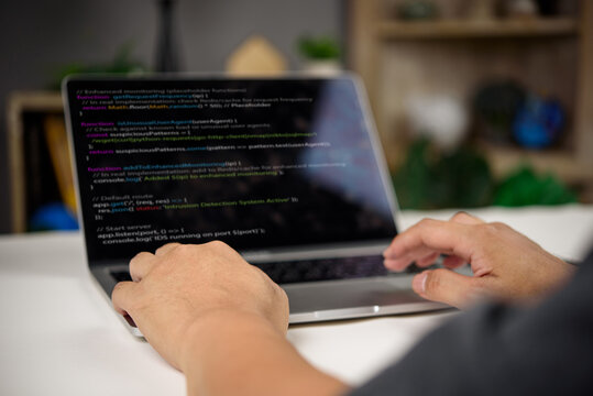 Developer working on intrusion detection system code in JavaScript with real-time monitoring and enhanced security features on laptop.