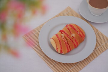 Delicious sweet bread with red icing on a plate with coffee
