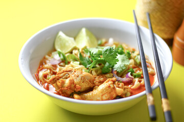 A delicious Thai dish, khao soi, featuring spicy noodle soup with chicken, vibrant veggies, and...