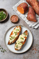 Baked sweet potatoes with creamy cheese topping and fresh herbs. Healthy food