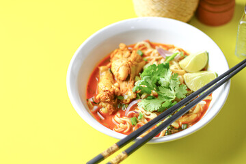 A delicious Thai dish, khao soi, featuring spicy noodle soup with chicken, vibrant veggies, and aromatic spices, served with fresh cilantro and lime.
