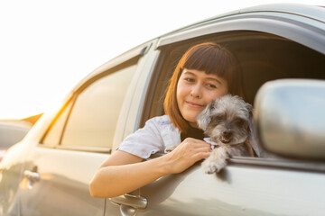 Young asian woman in casual outfit of cheerful with dog looking out of car window. Young female...