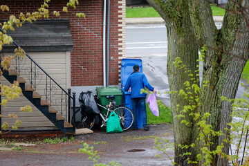 Un homme cherche des bouteilles vides dans les poubelles. Pauvreté urbaine.	