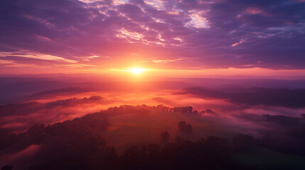 Obraz premium A breathtaking sunrise over a misty landscape, bathing the sky in vibrant hues of orange and purple.
