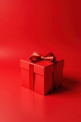 A single red gift box with a satin ribbon bow, sitting on a matching red background