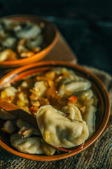 Traditional dumplings served in a rustic clay bowl with fried onions and steam rising, placed on burlap fabric in warm, moody lighting