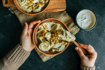 Traditional dumplings served with fried onions and meat in ceramic bowls on burlap with a bowl of...