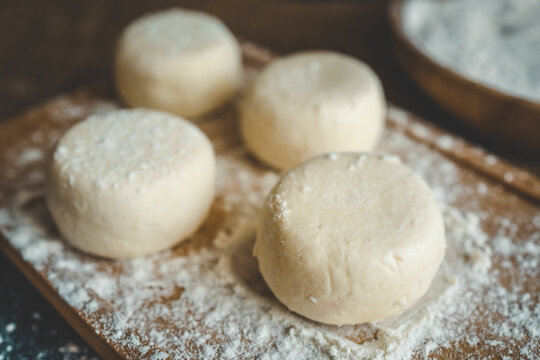 Raw dough rounds on a floured wooden board with a heart shape drawn in flour, flat lay of homemade baking preparation