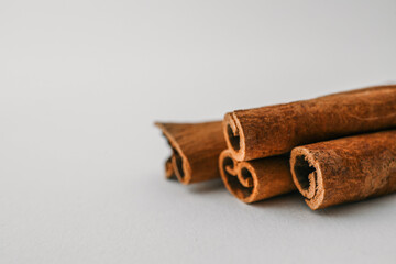 Cinnamon sticks arranged on a white background in soft natural light, showcasing texture and spice...