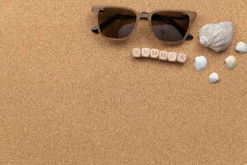 Summer beach vibes with sunglasses and seashells. Wooden blocks spelling summer