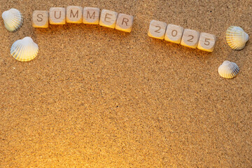 Wooden blocks spell summer 2025 surrounded by seashells on cork background