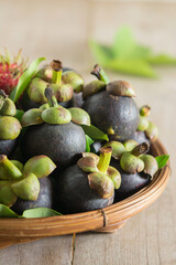 Fresh mangosteen fruits in bamboo basket placed on wooden table, Healthy organic tropical fruit