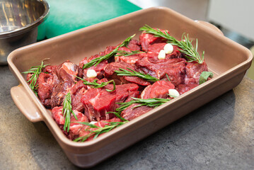 Raw beef with rosemary and garlic in baking tray.