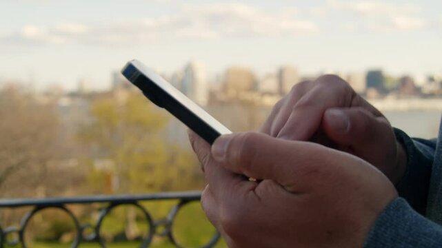 A man checks his phone while standing on a street at sunset, his face softly lit by the screen, capturing the essence of urban connectivity.
