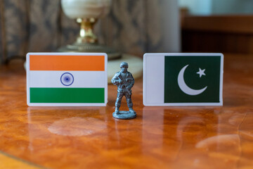 A tin soldier on the background of the flags of India and Pakistan. India Pakistan military conflict
