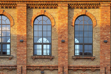 The arched windows of an old factory hall built of beautifully renovated bricks