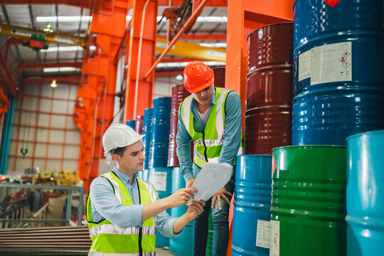 Industrial engineers inspect liquid storage drums in large-scale warehouse for export logistics, ensuring safety compliance, shipping standards, quality control of materials