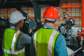 Engineers in high-visibility vests inspecting industrial control systems in modern factory, ensuring automation robotics, intelligent operations run under safety protocols, technical supervision