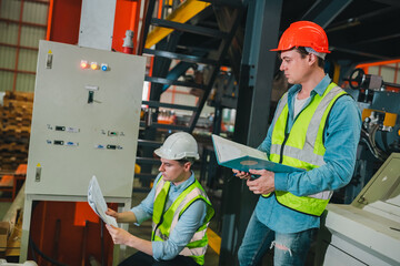 Engineers in high-visibility vests inspecting industrial control systems in modern factory, ensuring automation robotics, intelligent operations run under safety protocols, technical supervision