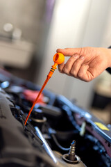 Technician checking dipstick for level oil in engine car in garage. Engine service check, oil dipstick detail in service. Engine problems, engine repair at a car repair shop