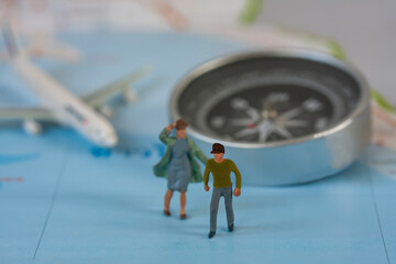 Selective focus of miniature tourist couple people walking on map with plastic toy airplane.