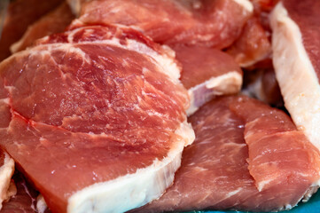 A close-up view of fresh raw pork chops, showcasing the natural marbling and rich red color of the meat. Perfect for food photography, recipe blogs, or illustrating cooking preparations.