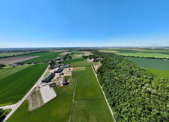 Luftbildpanorama im Fr&uuml;hling &uuml;ber K&ouml;nigshoven, Kaster und Bedburg mit Blick auf die Kirche St. Peter, Gut Hohenholz und den Hohenholzer Graben. Blauer Himmel, bl&uuml;hende Felder, sonnige Landschaft