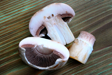 champignon mushroom cut in half and with the stem separated on a wooden surface