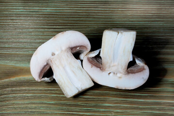 champignon mushroom cut in half on a wooden surface