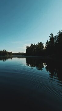 4K scene of a remote lake with reflecting water and silhouetted trees in Temagami, Ontario, Canada