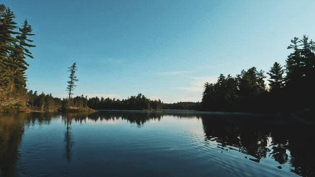 4K of a lake with reflecting water and silhouetted trees in Temagami, Ontario, Canada at sunset