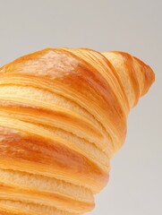 Close-up of a flaky, golden-brown croissant against a minimalist background.