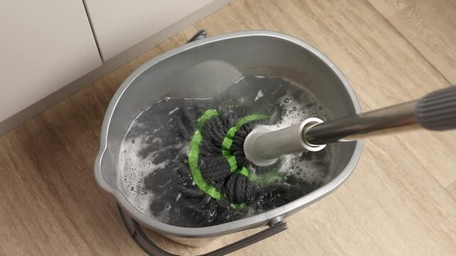 The floor mop is lowered into a bucket of water for subsequent cleaning.