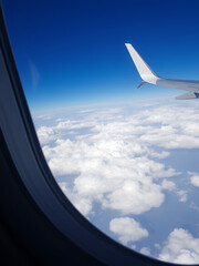 Passengers can enjoy a stunning view of a clear blue sky filled with fluffy clouds through an airplane window, showcasing the beauty of air travel
