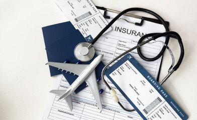 Medical tourism. Travel insurance application form, stethoscope, plane model and flight tickets on black wooden table, closeup
