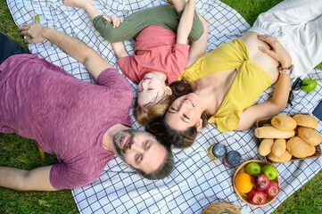 Top view of happy family spending time on holiday. mother, father and little son having picnic in...