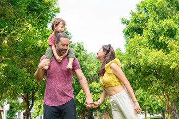 Obraz premium Happy Family. father, mother with little child in the park on a sunny summer day together. Son sitting on his father shoulders happy in vacation time.