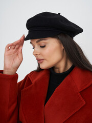 Young woman with long dark hair wearing a black beret and red coat tilting her head slightly, eyes...