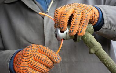 Male hands in gloves setting up manual lawn mower to clean grass. High quality photo