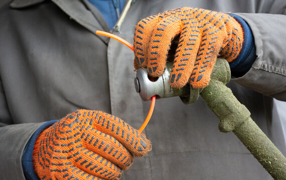 Male hands in gloves setting up manual lawn mower to clean grass. High quality photo