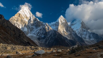 Obraz premium Majestic snow-capped mountains rising through white clouds under blue sky with golden sunlight, inspiring natural scenery with epic scale and high-definition clarity.